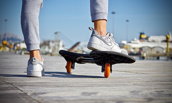 Eine Person steht mit einem Bein auf einem Skateboard